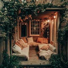 an outdoor living area with couches, pillows and potted plants on the side