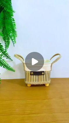 a basket sitting on top of a wooden table next to a potted green plant