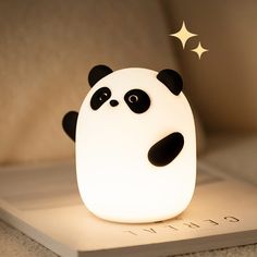 a panda bear night light sitting on top of a white book with stars above it