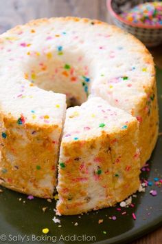 a cake with sprinkles is cut into slices on a green platter