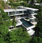 an aerial view of a modern house in the woods with trees surrounding it and swimming pool