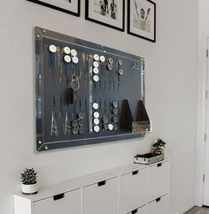 a wall mounted jewelry organizer in a white room with black and white pictures on the wall