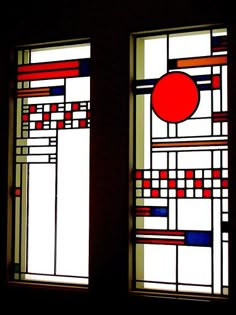 two stained glass windows with geometric designs on them in a dark room, one is red and the other is blue