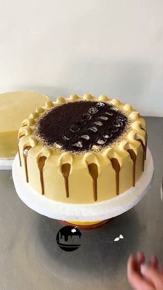 a cake with chocolate icing sitting on top of a metal table next to another cake