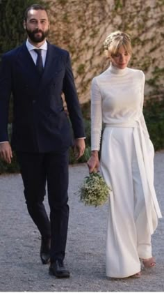 a man and woman walking down a road holding hands