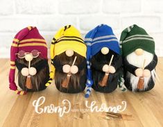 four knitted gnomes sitting on top of a wooden table next to each other