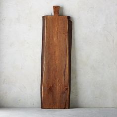 a wooden cutting board sitting on top of a white counter next to a wall mounted clock