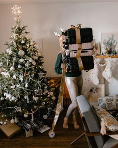 a woman carrying luggage in front of a christmas tree with presents wrapped around her neck