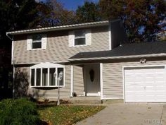 a two story house with white garage doors and gray siding on the front of it