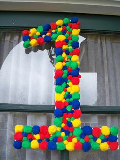 the letter j made out of pom - poms sits in front of a window