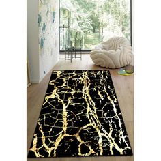 a black and gold area rug in a room with wood flooring, white walls and large windows