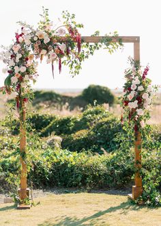 an outdoor wedding ceremony setup with flowers and greenery on the side of the aisle