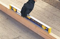 a pair of gloves on top of a piece of wood that is being held by a hand