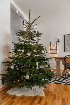 a small christmas tree in the corner of a room with wooden floors and white walls