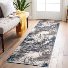 a living room area with a couch, chair and rug on the hardwood flooring