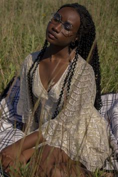 a woman sitting on top of a grass covered field