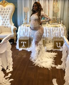 a pregnant woman standing in front of a table with white chairs and tables on it