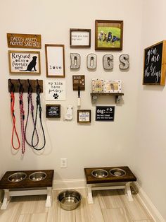 a dog's kennel with two dogs bowls and leashes on the wall