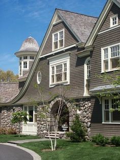 the house is made of wood and has white trim on the windows, along with stone walls