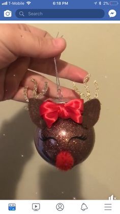 a hand holding a small mouse ornament with a red bow on it's head