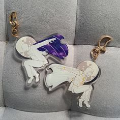 two keychains with cartoon characters on them sitting on a seat cushion in the back of a car