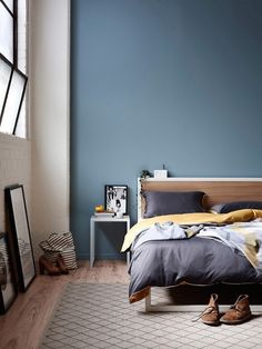 a bed room with a neatly made bed and blue walls