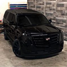 a black suv parked in front of a brick wall