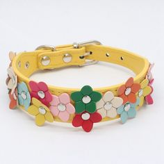 a yellow leather dog collar with colorful flowers on the front and sides, all decorated in different colors