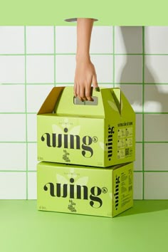 two boxes stacked on top of each other in front of a green tiled wall and floor