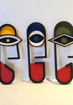 three metal sculptures with different shapes and colors on the top one has an eye in it