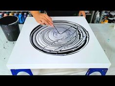 a person is using scissors to draw a design on a white table with blue legs