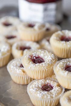 small pastries with powdered sugar and jelly toppings on a silver platter