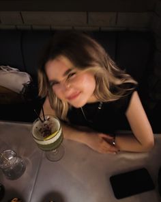 a woman sitting at a table with food and drinks in front of her, smiling