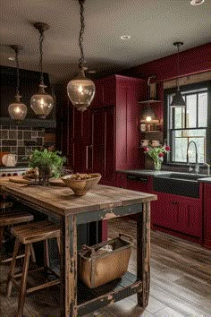 a kitchen with red cabinets and wooden table in front of an island that has two stools on it