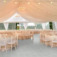 the inside of a large tent with tables and chairs set up for a formal function