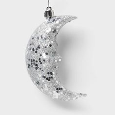 an ornament shaped like the moon with black and white dots hanging from it's side