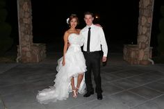 a bride and groom posing for a photo in front of an archway at night time