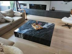 a living room filled with furniture and a large black marble coffee table on top of a hard wood floor