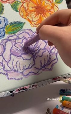 someone is drawing flowers on a canvas with crayons