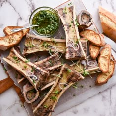 grilled fish and bread on a cutting board with pesto sauce in the middle