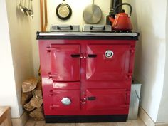 an old fashioned red stove with pots and pans on it's burners