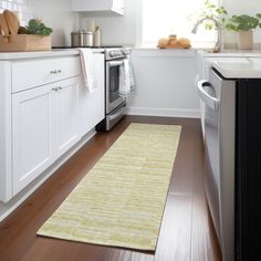 a clean kitchen with white cabinets and wood flooring is seen in this image from the doorway