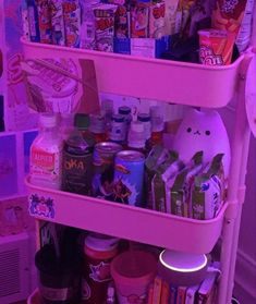 a shelf filled with lots of different types of food and drinks in pink lights next to a wall