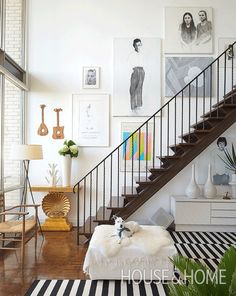 a dog is sitting on a footstool in front of a staircase