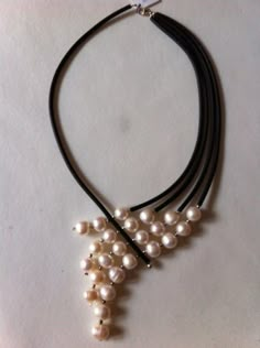 the necklace is adorned with pearls and black leather