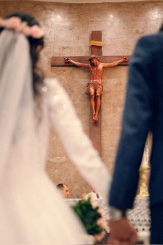 a bride and groom standing in front of a cross