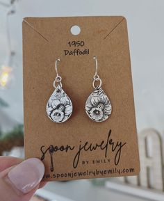 a pair of dangle earrings with flowers on them sitting in front of a card