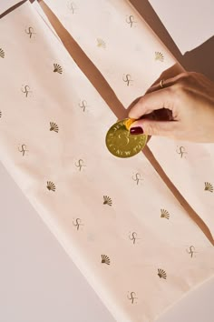 a hand holding a gold coin on top of a white table cloth with palm tree designs