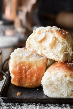 three rolls stacked on top of each other on a black tray next to a cup of coffee