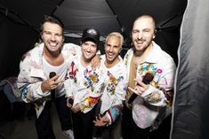 three men in white shirts and black hat standing under an umbrella with their cell phones